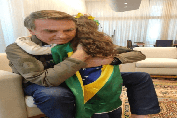 Criança enrolada com a bandeira do Brasil faz oração na cabeça do presidente Jair Bolsonaro